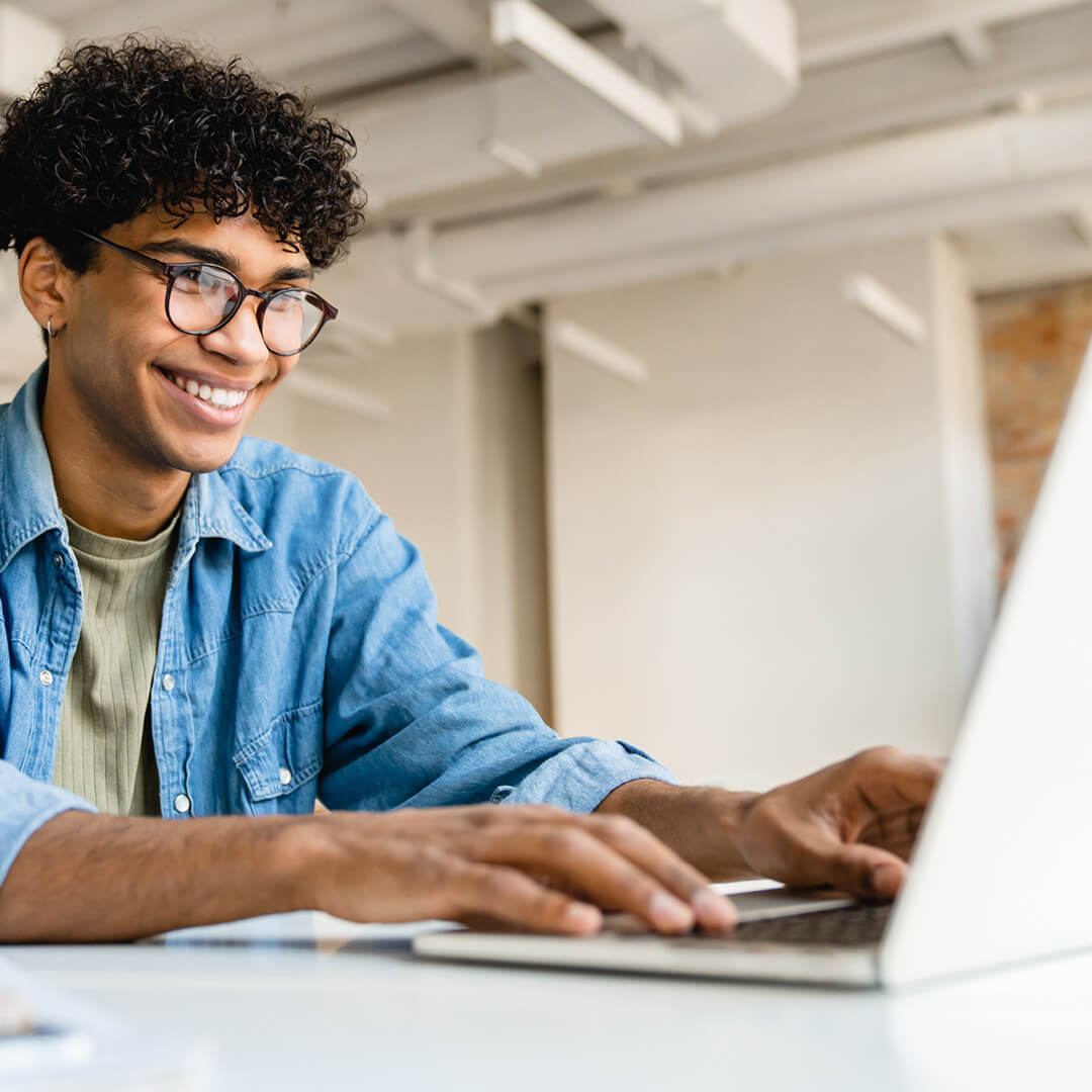 Smiling person working on laptop.